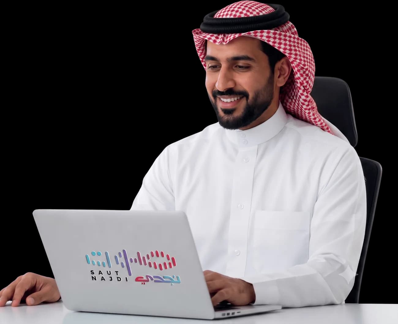 موظف سعودي يبتسم أمام جهاز لابتوب يحمل شعار صوت نجدي